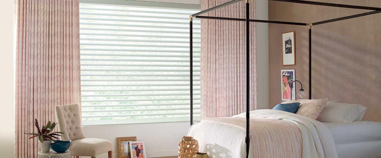 Four poster bed with pink and white window coverings.