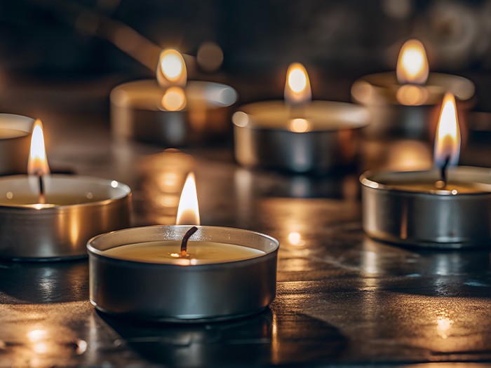 Plusieurs bougies chauffe-plat allumées sur une table dans une pièce faiblement éclairée.