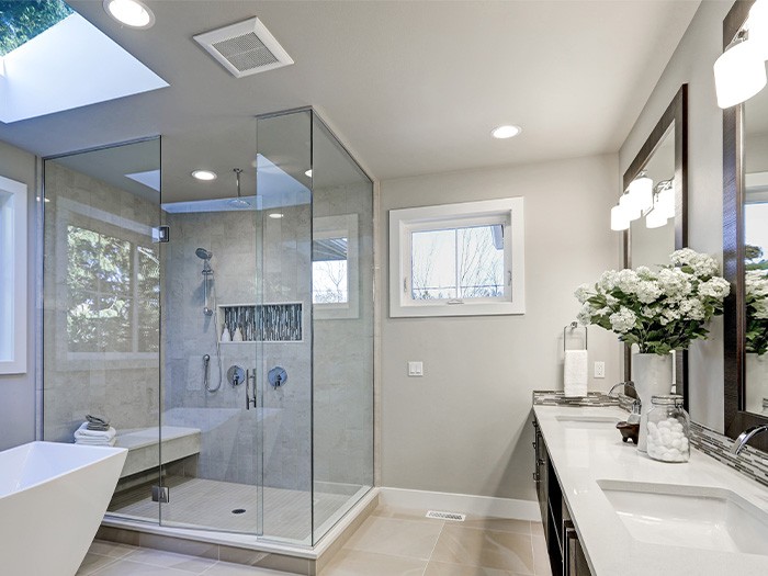 Grande salle de bains avec deux meubles-lavabos et une grande douche en verre.