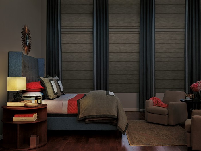 Chambre à coucher sombre dont les hautes fenêtres sont équipées de stores romains modernes VignetteMD.